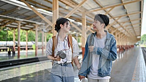 A lovely young Asian couple enjoys talking while walking along the platform to catch their train