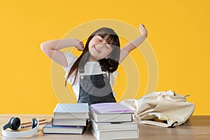 A lovely young Asian girl is stretching her arms, feeling tired after doing homework