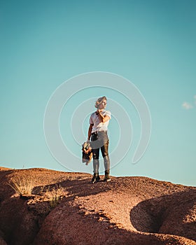 A lovely young boy in short sleeves looking to the horizon on a sandy mountain