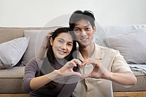 Lovely young couple asian is making heart sign with hands at home. Valentine day celebration