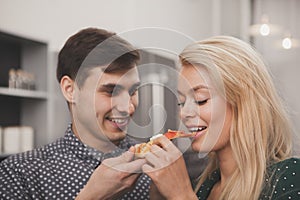 Lovely young couple eating pizza together at the kitchen