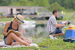 Lovely young couple fishing by lake