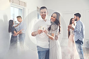 Lovely young couple with glasses of champagne at party