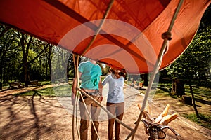 Lovely young couple jumping behind the bicycle with red dirigible in the park, general plan with wide angle