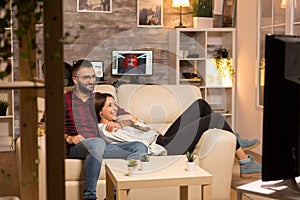 Lovely young couple relaxing on couch and watching a movie on tv