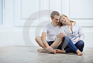 Lovely young couple sitting on floor and smiling