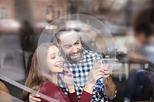 Lovely young couple spending time together in cafe, view from outdoors