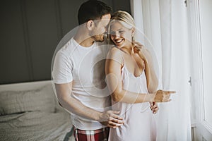 Lovely young couple standing by the window at morning