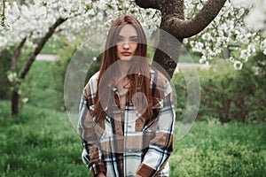 lovely young fashionable lady in blooming garden with white trees
