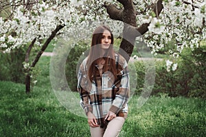 lovely young fashionable lady in blooming garden with white trees