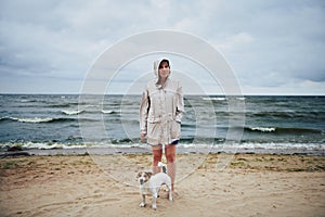 Woman in jacket looking at dog near sea