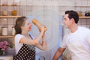 Lovely young happy caucasian couple or lover playful fight in kitchen together. Funny boyfriend and girlfriend have fun in kitchen