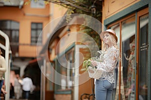 A Lovely young lady in summer hat resting in open-air cafe propped face with hand and waiting friend.