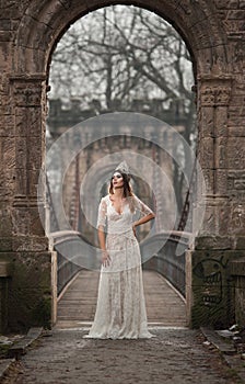 Lovely young lady wearing elegant white dress enjoying the beams of celestial light and snowflakes falling on her face.