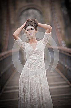 Lovely young lady wearing elegant white dress enjoying the beams of celestial light and snowflakes falling on her face