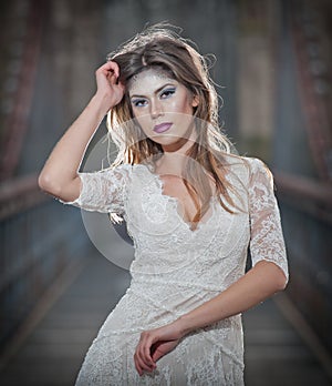 Lovely young lady wearing elegant white dress enjoying the beams of celestial light and snowflakes falling on her face