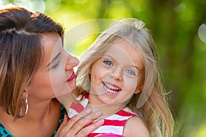 Lovely young mom and daughter in warm sunny summer day. Happy family mother and child little daughter playing and