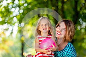 Lovely young mom and daughter in warm sunny summer day. Happy family mother and child little daughter playing and