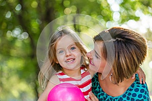 Lovely young mom and daughter in warm sunny summer day. Happy family mother and child little daughter playing and