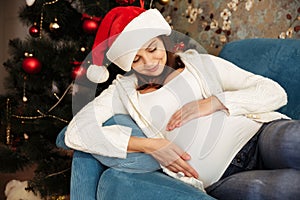 Lovely young pregnant woman in christmas hat