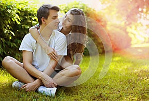 Lovely young teen couple in love having fun on lawn in park