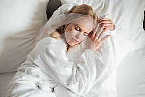 Lovely young woman in bathrobe sleeping on bed