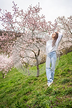 Lovely young woman in a blooming pink and white garden Petrin in Prague, spring time in Europe