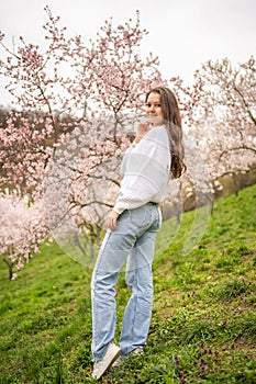 Lovely young woman in a blooming pink and white garden Petrin in Prague, spring time in Europe