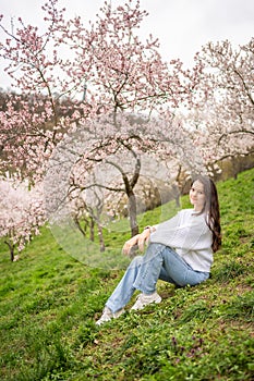 Lovely young woman in a blooming pink and white garden Petrin in Prague, spring time in Europe