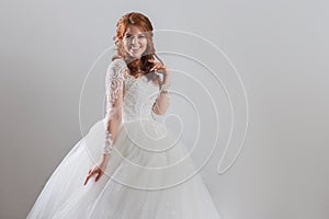 Lovely young woman bride in lavish wedding dress. Light background.