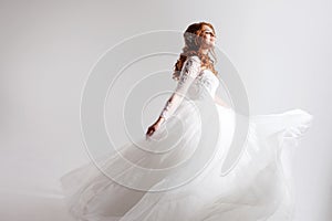 Lovely young woman bride in a lavish wedding dress. Light background.