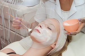 Lovely young woman with cream mask in a beauty parlour photo