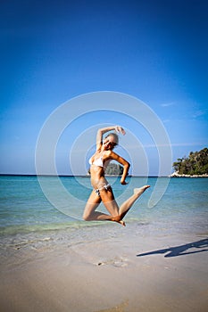 Lovely young woman jumping on the sunny Kata beach, Phuket, Tha