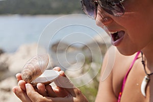 Lovely young woman with seashell on the sea coast