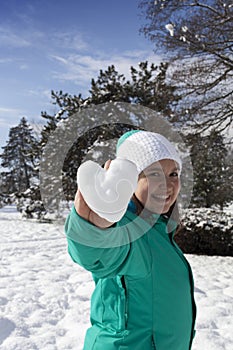 Lovely young woman showing snow heart