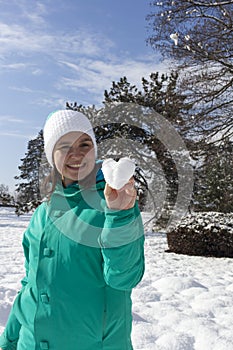 Lovely young woman showing snow heart