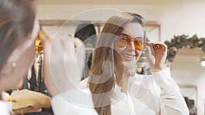 Lovely young woman trying new sunglasses at fashion store