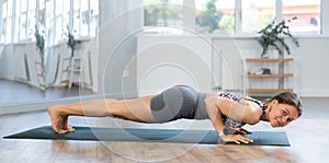 Lover of active lifestyle on yoga mat perform doing Chaturanga dandasana in gym