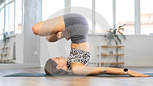 Lover of active lifestyle on yoga mat perform doing Padma Salamba Sarvangasana in gym