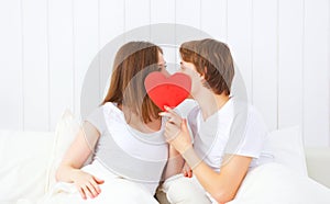 Lover couple kissing with a red heart in bed