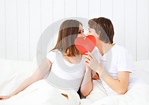 Lover couple kissing with a red heart in bed