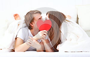 Lover couple kissing with a red heart in bed