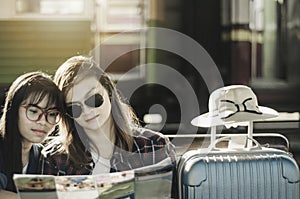 Lovers of Asian women lesbian LGBT couples,View map on old bench In platform of train station, concept of travel holiday pleasure