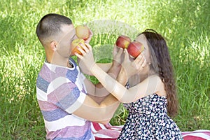 Lovers boy and girl dabble apples close each others eyes. emotions. summer picnic