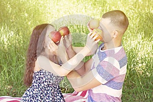 Lovers boy and girl dabble apples close each others eyes. emotions. summer picnic