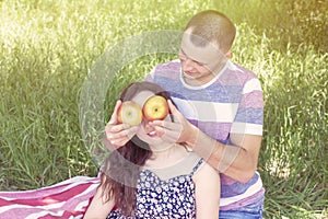 Lovers boy and girl dabble apples close each others eyes. emotions. summer picnic