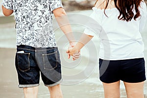 Lovers couple holding hands and walking on the beach together