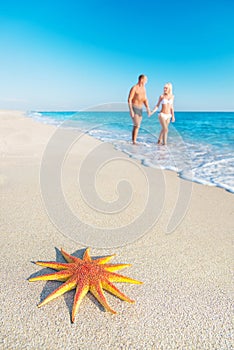 Lovers couple at sandy sea beach with red starfish