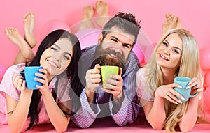 Lovers drinking coffee in bed. Lovers in bed concept. Man and women, friends on smiling faces lay, pink background