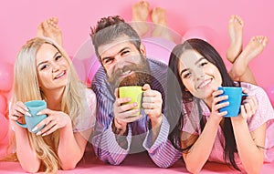 Lovers drinking coffee in bed. Lovers in bed concept. Man and women, friends on smiling faces lay, pink background